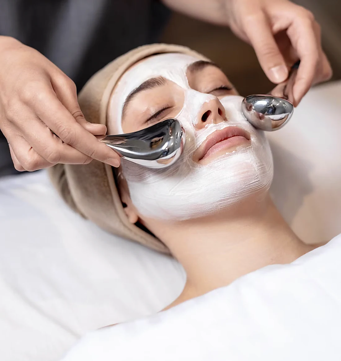 A guest receiving a facial treatment with cooling massage tools